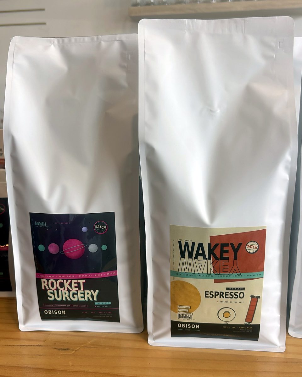 Two Obison coffee bags, Rocket Surgery and Wakey Wakey Espresso, on the counter at Obison's stall in Origins Market, Busselton.